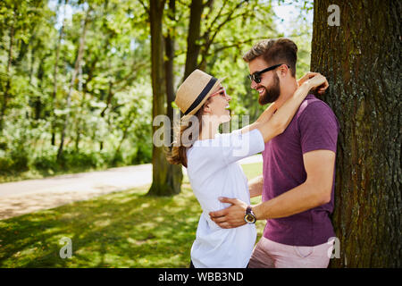 Junges Paar umarmen und lehnte sich an einen Baum im Park Stockfoto