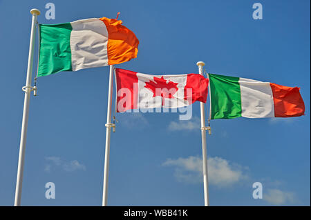 Die Flagge von Italien, Kanada und in der Republik Irland (Eire) fliegen auf fahnenmasten vor blauem Himmel. Stockfoto