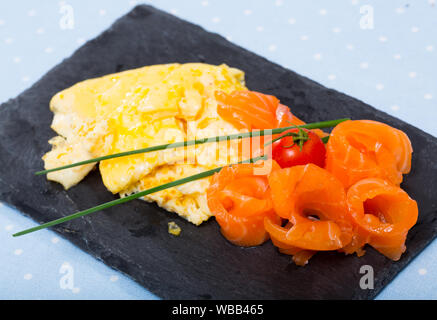 Omelette mit Lachs mit frischem Schnittlauch und Cherry Tomaten auf schwarzem Schiefer Board eingerichtet Stockfoto