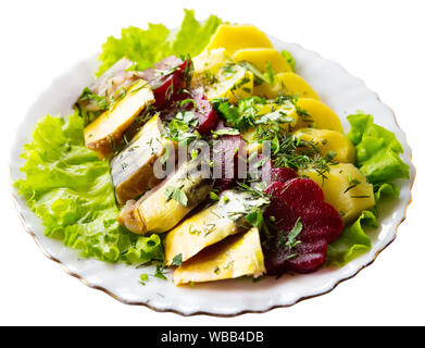 Traditionelle russische Vorspeise geschnittener geräucherter Makrele serviert auf salatblätter mit gekochten Kartoffeln und Rote Bete. Auf weissem Hintergrund Stockfoto