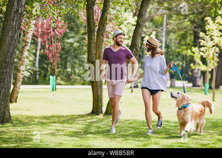 Reizende junge Paar, dass im Park mit ihrem Hund im Sommer Stockfoto