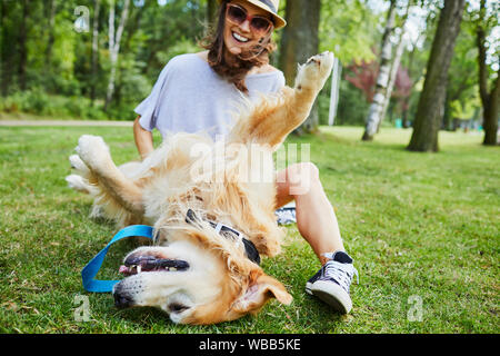 Fröhliche junge Frau, die das Spielen mit Ihrem Hund draußen im Park Stockfoto