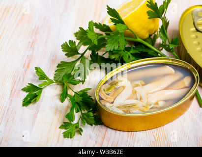 Gourmet canned natürlichen marinen Muscheln Solen auf Holztisch mit frischer Petersilie und Zitrone. Mediterran Meeresfrüchte Stockfoto