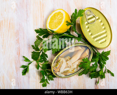 Meeresfrüchte Vorspeise. Öffnen der erhaltenen natürlichen Muscheln razorshell (ensis) mit Kräutern und Zitrone auf hölzernen Tisch Stockfoto