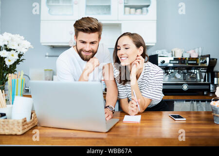 Paar freundliche Besitzer kleiner Unternehmen kümmert sich um die Finanzen und Zahlungen mit Notebook und Notepad in ihrem Restaurant Stockfoto