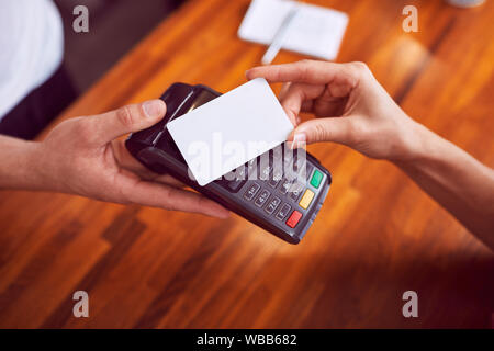 Closeup Schuss weiblicher Hand Bezahlen mit Karte mit Holz- Zähler im Hintergrund Stockfoto