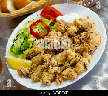 Spanische Meeresfrüchte Teller chipirones a la Andaluza, zerschlagenen Tintenfisch mit frischem Salat serviert. Stockfoto