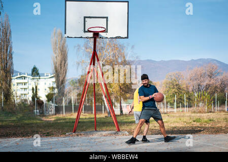 Männer Basketball spielen im Park an einem sonnigen Herbsttag Stockfoto