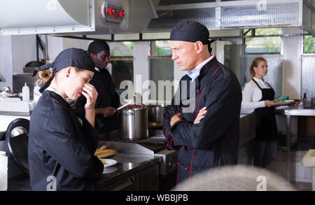 Wütend männlichen Chef mit seinem weiblichen Assistant in der gewerblichen Küche Stockfoto