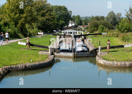 Devizes, Wiltshire, England, UK. August 2019. Zwei narrowboats reisen zusammen durch eine der Sperren auf der Caen Hill Flug von Schlössern. Warten auf t Stockfoto