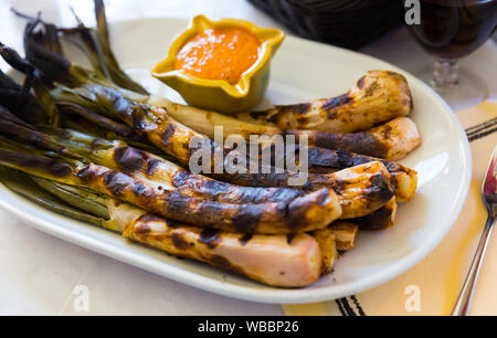 Gebratene Calcots Zwiebeln serviert auf Platte mit Romesco Sauce - traditionelle katalanische Wintergericht Stockfoto