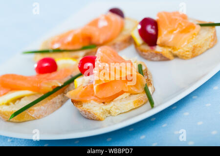 Tapas mit Lachsfarbenen mit Zitronenscheibe, Cranberry und Schnittlauch Stockfoto
