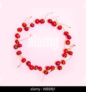 Rahmen aus Süßkirschen auf Licht auf einem rosa Hintergrund. Ansicht von oben Stockfoto