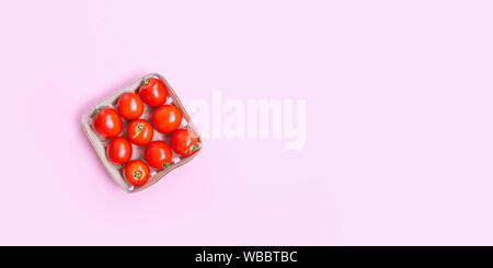 Frische reife rote Tomaten in einem hölzernen Korb auf einem rosa Hintergrund mit Platz für Text Stockfoto