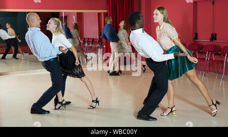 Junge lächelnde Menschen üben heftige jive Bewegungen im Tanz Klasse Stockfoto