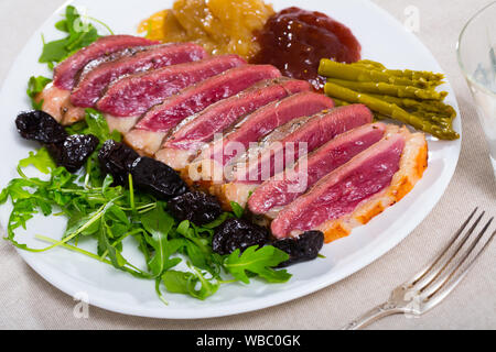 Leckere gegrillte Ente magret Filet mit grünen, Pflaumen, Spargel und Sauce serviert. Stockfoto