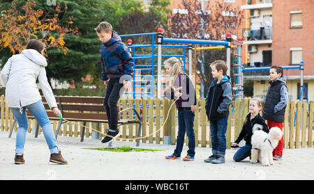 Positive Kinder spielen im springen Seil Spiel in Park und Spaß haben Stockfoto