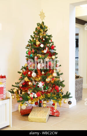 Weihnachtsbaum mit Kugeln und Dekorationen und Geschenke unter den Baum in einem UK Home eingerichtet Stockfoto