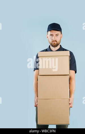 Lieferung Mann in Uniform hält Stapel von Kartons Stockfoto
