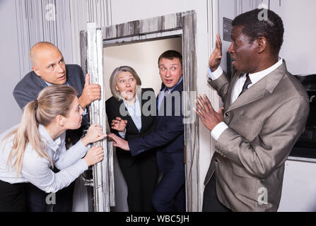 Betonte Geschäftsleute Schließen der Klappe auf der Suche Zimmer STILISIERTE unter Bunker, so dass andere Menschen nicht ein. Сoncept auf Druck der Opposition Executiv Stockfoto