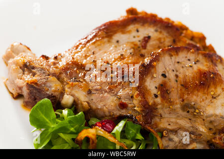 Gegrilltes Schweinefleisch Rib Steak chop auf weissem Teller mit Linsen, Brei und Salat Beeren Stockfoto