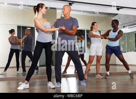 Junge lächelnde Menschen üben heftige jive Bewegungen im Tanz Studio Stockfoto