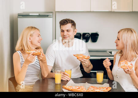 Junge Freunde, Party zu Hause, essen Pizza, trinken Fruchtsaft und lächelnd. Die fröhliche Gesellschaft von Jugendlichen in der Küche ruht. Radeln Stockfoto