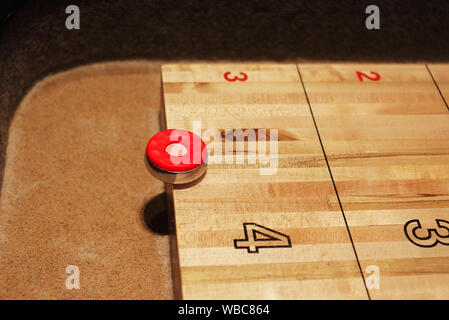 Red shuffleboard Disc auf der Tabelle auf fünf Punkte markieren. Shuffleboard Spiel im Gange, Nacht, Innenraum. Stockfoto