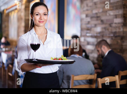 Professionelle happy Kellnerin holding Serviertablett für Gäste Stockfoto