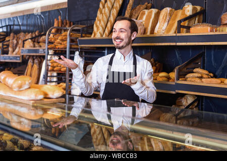 Junge gerne fröhliche Mann Verkäufer anzeigen Sortiment der Bäckerei Stockfoto