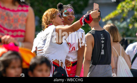 Zwei Karneval - goers Nehmen ein selfie. Die wichtigsten Ereignisse der Notting Hill Carnival 2019 erhielt unterwegs am Sonntag, mit über einer Million revellers schlagen die Straßen von West London, unter den Schwimmern, maskierten, Steel Bands und Sound Systeme. Stockfoto