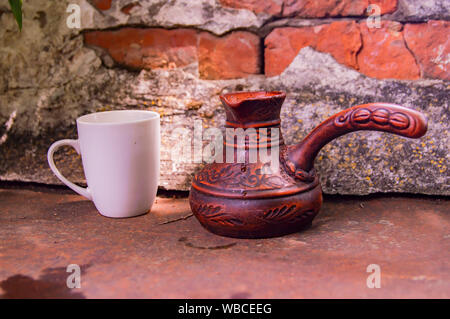 Ton Turk für Kaffee und eine weiße Schale auf die Wand im Hintergrund. Hintergrund. Stockfoto