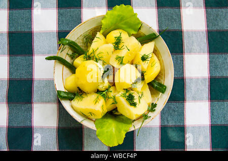 Kartoffeln mit Kräutern in eine Platte auf eine Tischdecke in einem Käfig. Hintergrund. Stockfoto