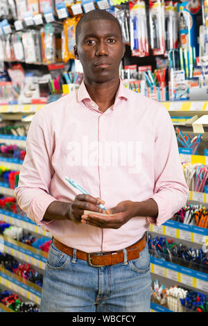 Feine afrikanischer Mann mit Kugelschreiber und Bleistifte in Bürobedarf shop Stockfoto