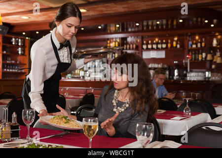 Weibliche kunden Unzufriedenheit mit dem bestellten Teller durch junge Kellnerin im Restaurant serviert. Stockfoto