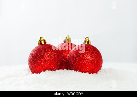 Drei rote Kugeln auf weißem Schnee Hintergrund. Weihnachten Zusammensetzung Stockfoto