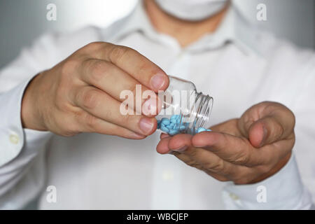 Arzt, Pillen, Arzt in der medizinischen Maske Holding in den Händen Flasche mit blauen Tabletten. Konzept der Dosis von Medikamenten, Vitaminen, Viagra, Apotheke Stockfoto