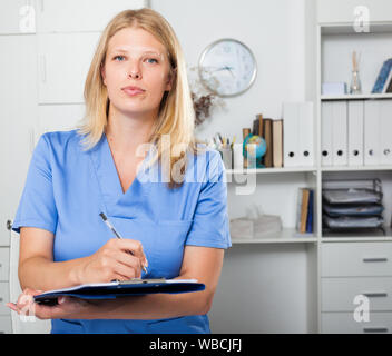 Lächelnd weibliche Krankenschwester in formale Abnutzung Registrierung Informationen in Form Stockfoto