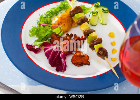 Gegrilltes Huhn Herz am Spieß mit Avocado mit gebratenen Pfifferlingen und Gemüse serviert. Stockfoto