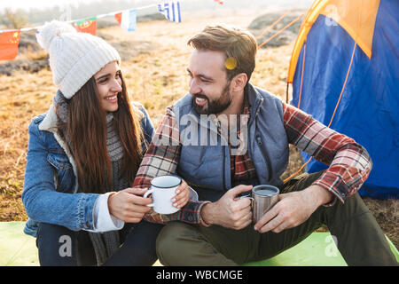 Foto von glückliches junges Paar außerhalb mit Zelt im Freien alternative Ferienhäuser Camping über Berge trinken heißen Tee. Stockfoto