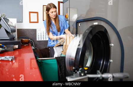 Effiziente Frau in Uniform die Kleidung von Waschmaschine Wäscheservice Stockfoto