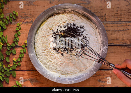 Schüssel mit Zutaten für eine Torte mit Schokolade Chips auf einer hölzernen Oberfläche machen Stockfoto