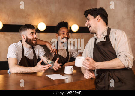 Drei fröhliche Männer baristas im Coffee Shop, Kaffee trinken in der Pause Stockfoto