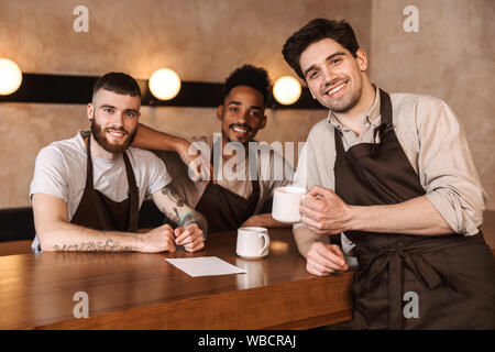 Drei fröhliche Männer baristas im Coffee Shop, Kaffee trinken in der Pause Stockfoto