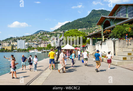 Montreux, Schweiz - 26. Juli 2019: Leute um die Statue von Freddie Mercury, der Sänger der berühmten Band Queen. Touristen fotografieren. Promenade am Genfer See. Beliebte Touristenattraktion. Stockfoto