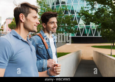 Zwei lächelnde junge Männer Freunde gekleidet beiläufig Zeit zusammen verbringen in der City, wenige Stockfoto