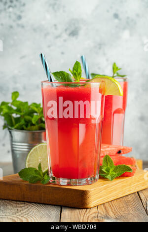 Wassermelone Slushie mit Limette und Minze, sommerlicher erfrischender Drink in hohen Gläsern auf hellblauem Hintergrund. Süßer, kalter Smoothie Stockfoto