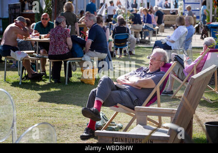 Festivalbesucher genießen Sie den Sonnenschein in Charlotte Square Gardens an Der 2019 Edinburgh International Book Festival, Edinburgh. Stockfoto