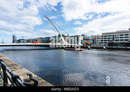 Ein Sightseeing Kreuzfahrt Schiff unter der Samuel Beckett Brücke über den Fluss Liffey in Dublin, Irland. Stockfoto