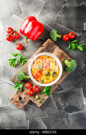 Frittata mit Brokkoli in Keramik. Frittata mit Brokkoli, süßer Paprika und Tomaten in zwei keramischen Formen zum Backen. Italienische Omelette mit v Stockfoto